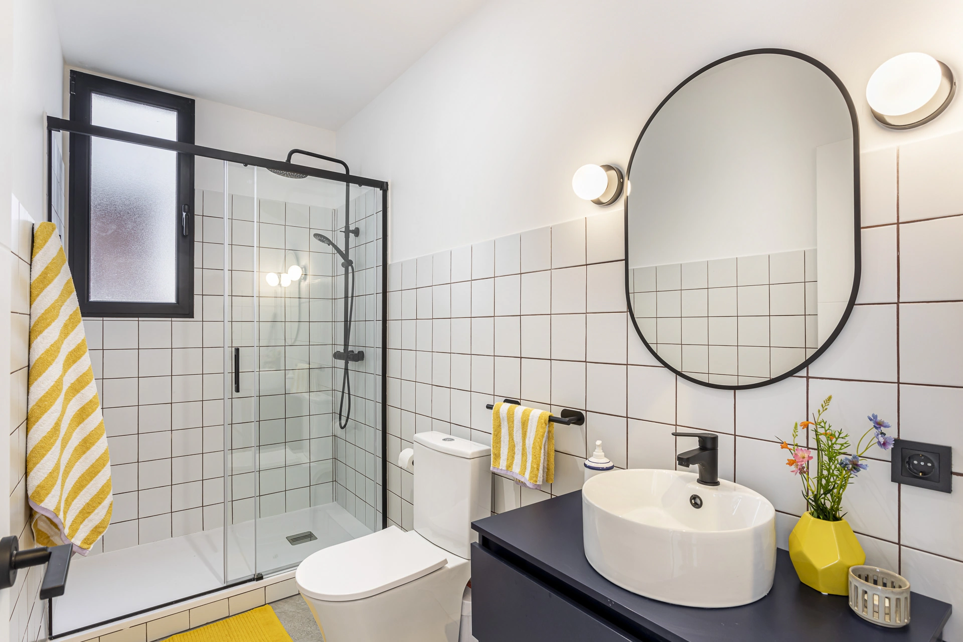 Baño reformado con ducha de perfilería negra y mueble suspendido