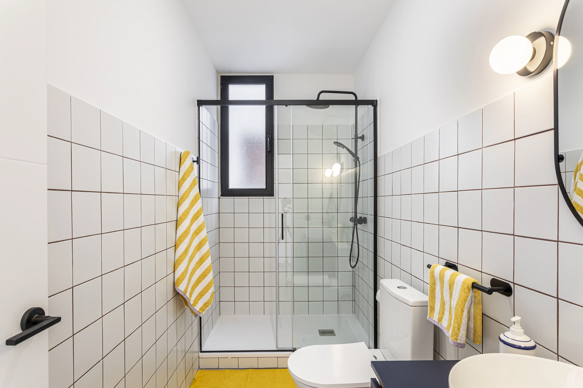 Vista completa del baño con ducha, lavabo y acentos amarillos