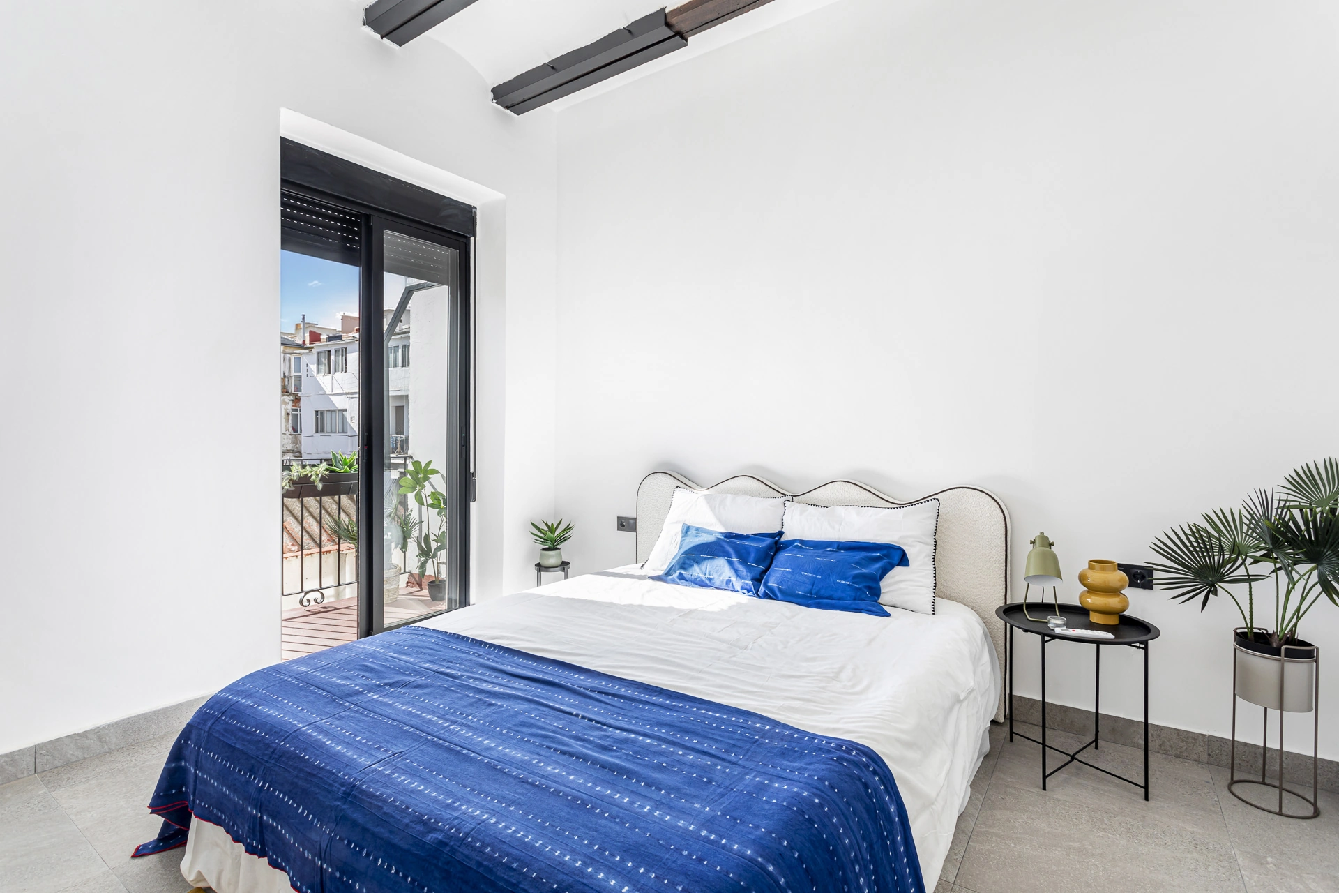 Dormitorio reformado con acceso al balcón y textiles azules
