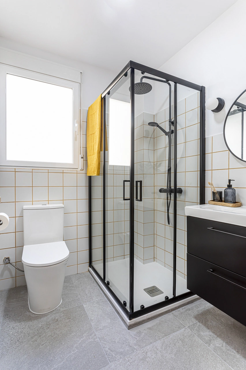Baño completo con ducha de perfilería negra y azulejo blanco